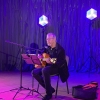 Artysta z gitarą występujący na scenie.