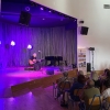 Artysta z gitarą występujący na scenie oraz publiczność.