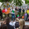 mężczyzna na tle kolorowych malowanych ptaków mówi do mikrofonu przed publicznością w parku