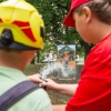 dwie osoby leją wężem strażackim wodę do celu