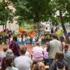 dziewczynki w kolorowych spódniczkach na scenie przed publicznością, po bokach sceny flagi organizatorów