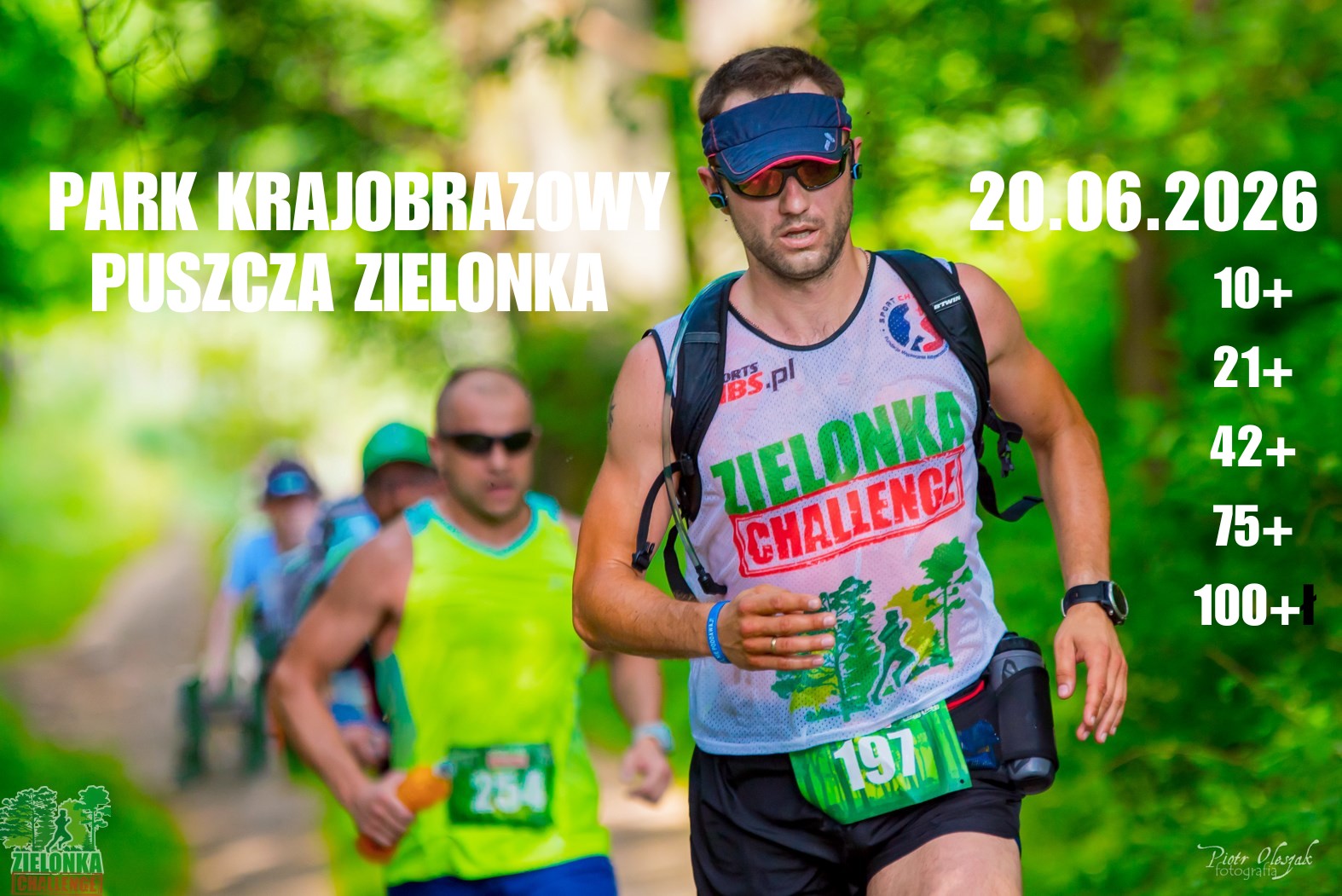 zdjęcie przedstawia zawodników podczas biegu, na pierwszym planie mężczyzna w okularach słonecznych, koszulce z logiem zawodów i daszkiem na głowie chroniącym od słońca