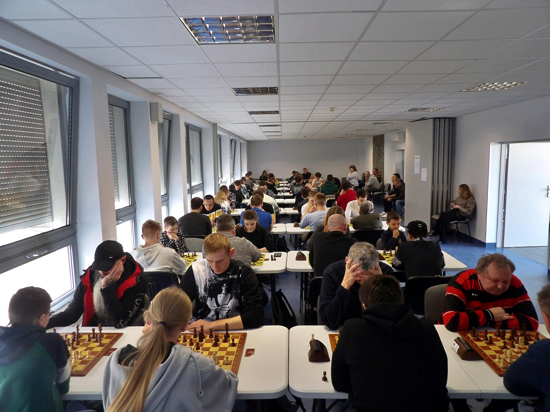 [obraz] Szachiści przy stołach, szachownice, zegary.